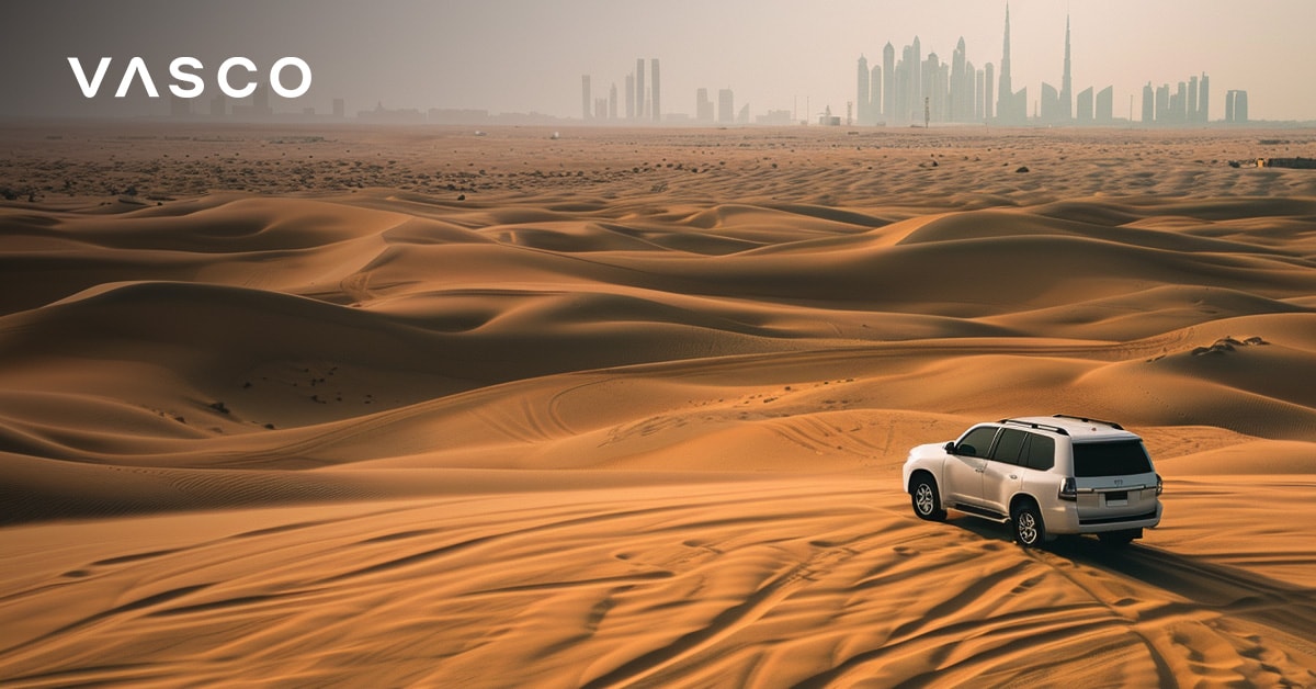 SUV vozi kroz pustinju Dubaija s gradskom panoramom u daljini